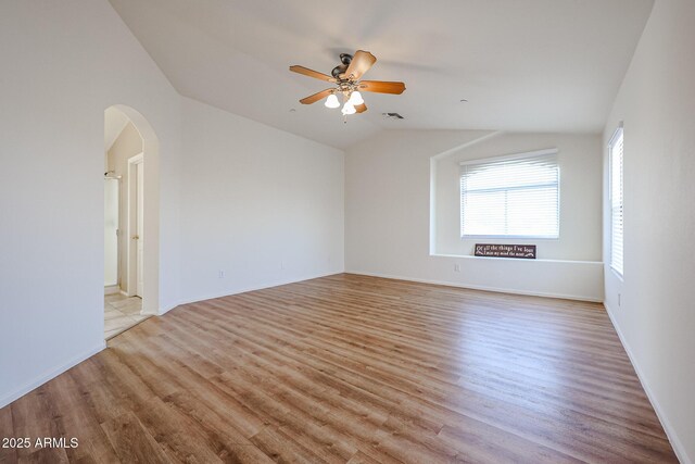 unfurnished room featuring light wood-type flooring, a ceiling fan, visible vents, lofted ceiling, and arched walkways