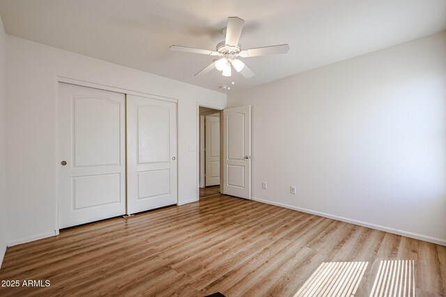 unfurnished bedroom with a closet, baseboards, ceiling fan, and wood finished floors