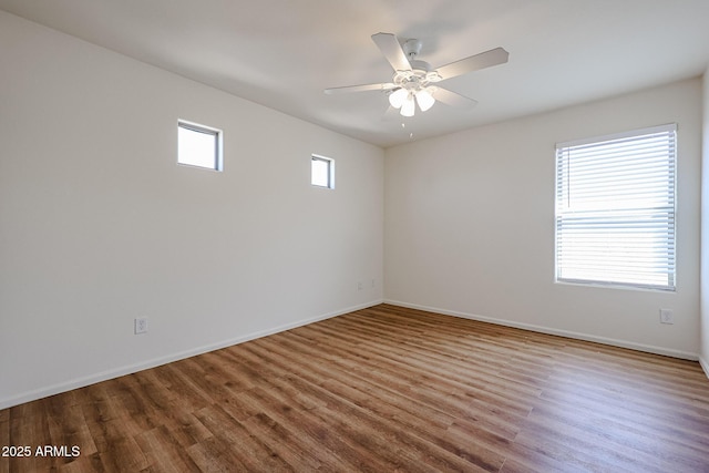 empty room with wood finished floors, baseboards, and a ceiling fan