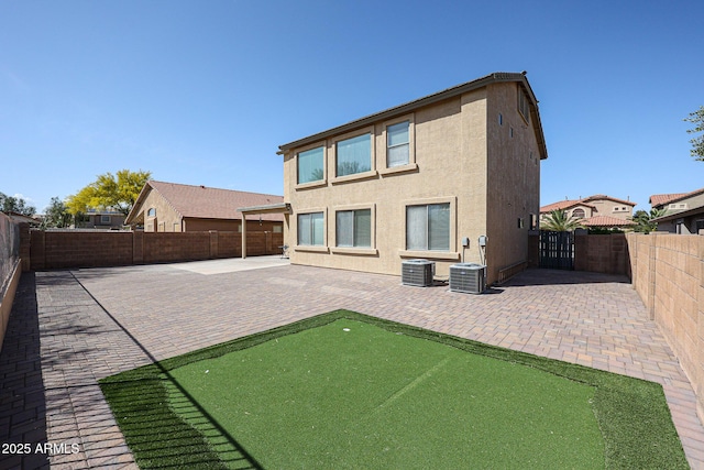 back of house featuring a patio area, a fenced backyard, central AC unit, and stucco siding