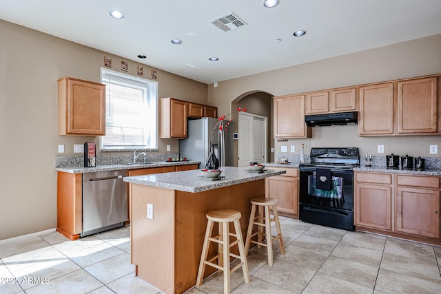 kitchen featuring visible vents, a center island, a sink, under cabinet range hood, and stainless steel appliances