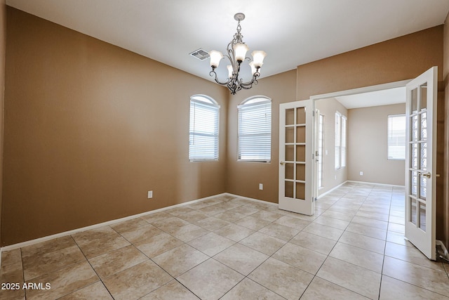 empty room featuring light tile patterned floors, plenty of natural light, a notable chandelier, and visible vents
