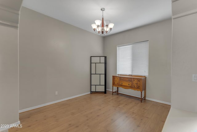 spare room with light hardwood / wood-style floors and a chandelier