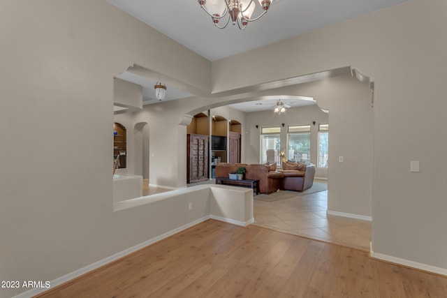 interior space with ceiling fan with notable chandelier and light wood-type flooring