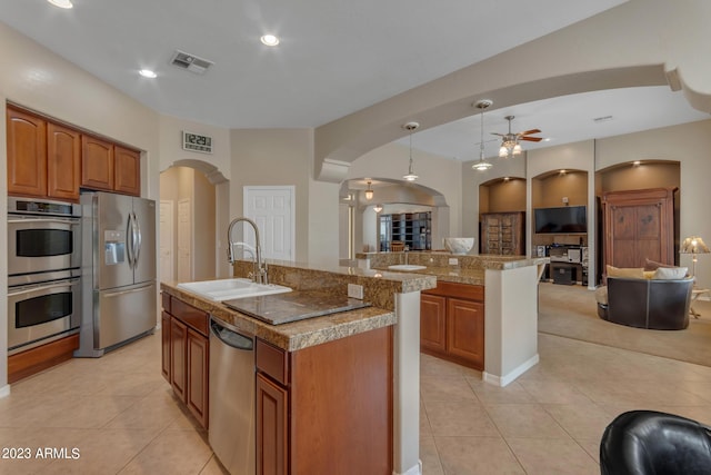 kitchen with a center island with sink, sink, appliances with stainless steel finishes, and hanging light fixtures