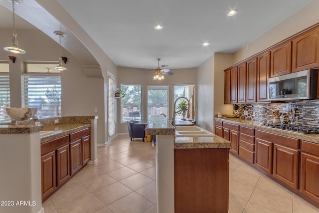 kitchen featuring appliances with stainless steel finishes, light tile patterned flooring, sink, hanging light fixtures, and decorative backsplash