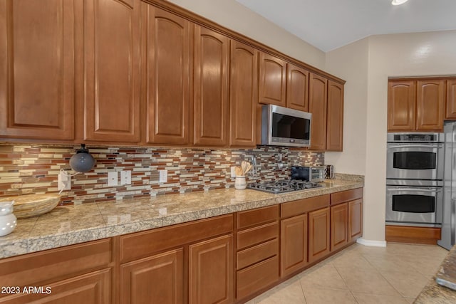 kitchen with appliances with stainless steel finishes, tasteful backsplash, and light tile patterned flooring