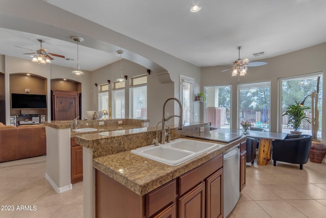 kitchen featuring decorative light fixtures, sink, a wealth of natural light, and an island with sink