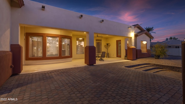 back house at dusk featuring a patio