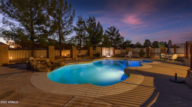 pool at dusk with a patio area