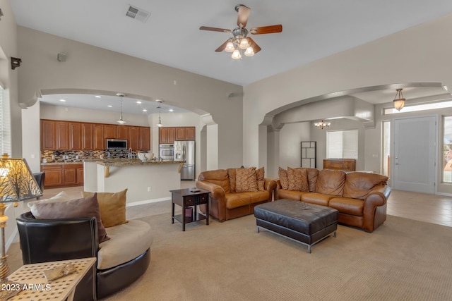 living room with ceiling fan with notable chandelier and light tile patterned floors