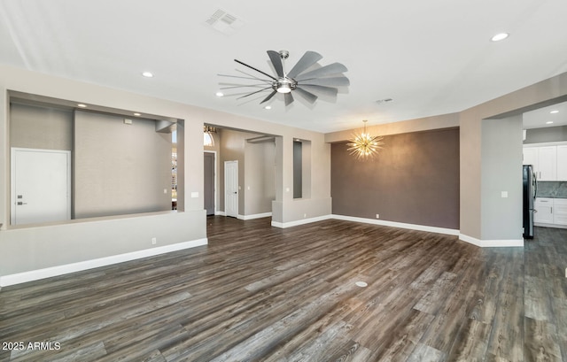 unfurnished living room with ceiling fan with notable chandelier and dark hardwood / wood-style floors