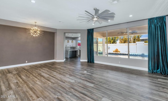 unfurnished living room with ceiling fan with notable chandelier and wood-type flooring