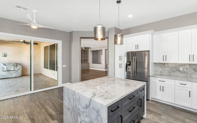 kitchen with decorative light fixtures, white cabinetry, backsplash, stainless steel fridge with ice dispenser, and light stone countertops