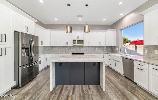 kitchen with appliances with stainless steel finishes, white cabinets, light stone countertops, and sink