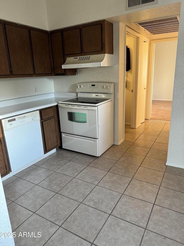 kitchen featuring light tile patterned floors, dark brown cabinets, and white appliances