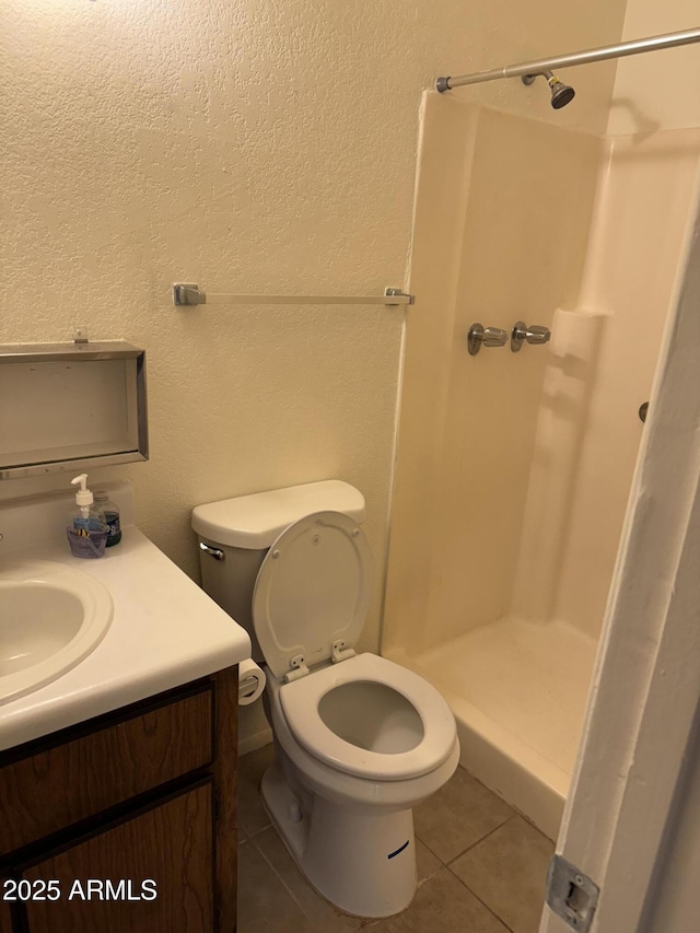 bathroom featuring walk in shower, vanity, tile patterned floors, and toilet