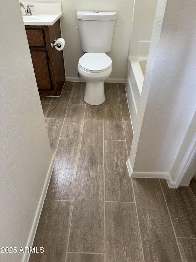 bathroom with a washtub, toilet, and vanity