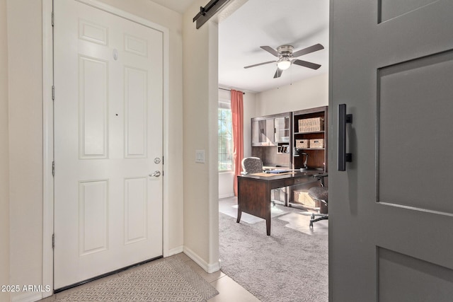 carpeted office space with ceiling fan and a barn door