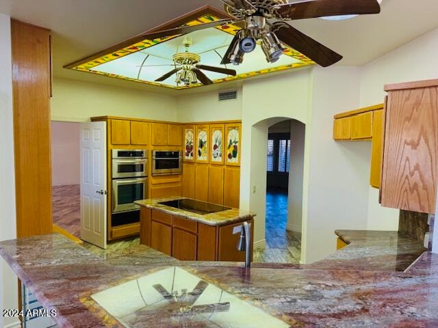 kitchen with kitchen peninsula, black electric stovetop, stainless steel double oven, ceiling fan, and lofted ceiling