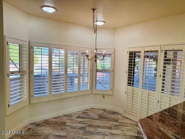 unfurnished dining area with a chandelier and hardwood / wood-style flooring