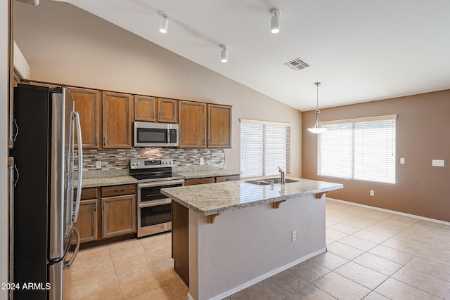 kitchen with stainless steel appliances, a kitchen island with sink, sink, decorative light fixtures, and lofted ceiling