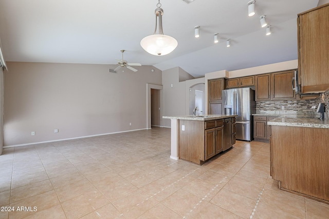 kitchen featuring ceiling fan, stainless steel appliances, hanging light fixtures, light stone counters, and a kitchen island