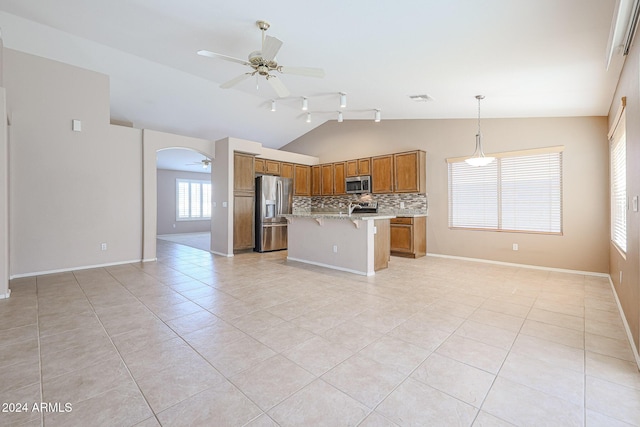 kitchen with a kitchen bar, appliances with stainless steel finishes, decorative light fixtures, a center island, and lofted ceiling