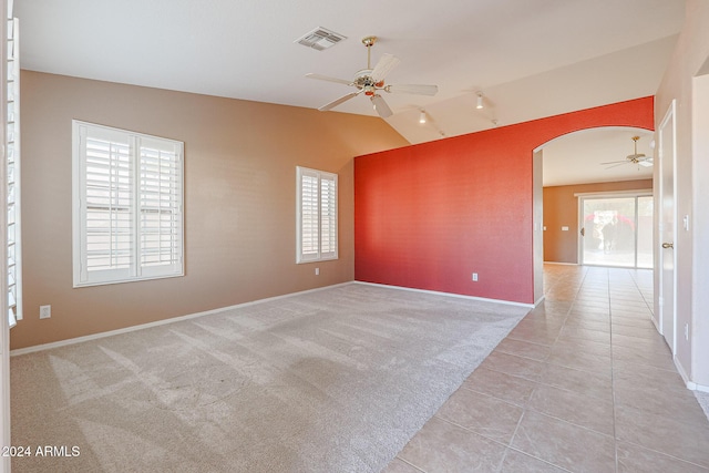 spare room featuring light colored carpet, plenty of natural light, lofted ceiling, and ceiling fan