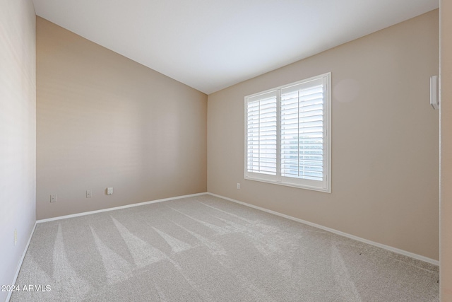 empty room with light colored carpet and vaulted ceiling