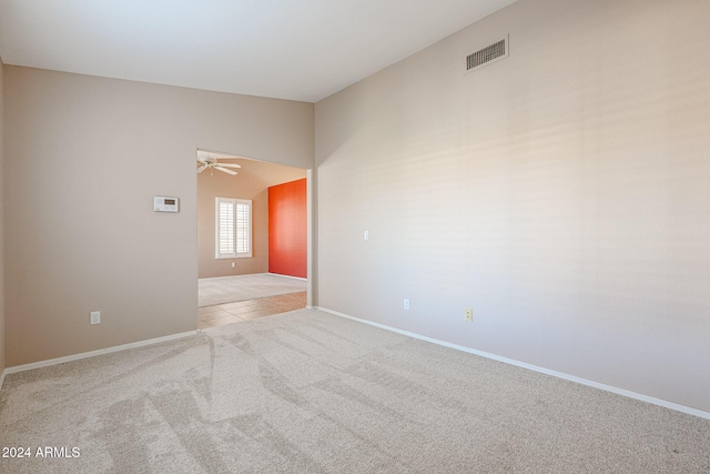 empty room with ceiling fan, light colored carpet, and vaulted ceiling