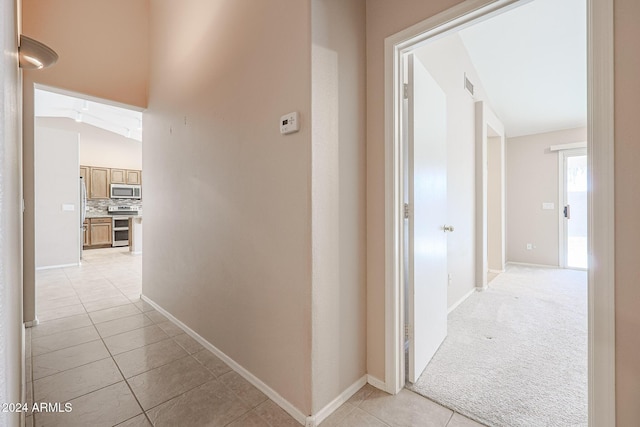 corridor featuring light colored carpet and vaulted ceiling