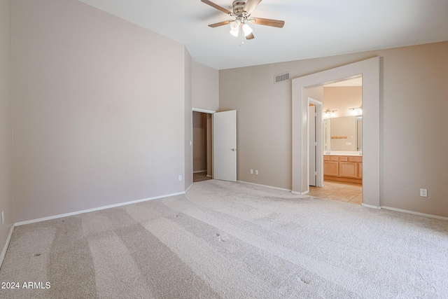 unfurnished bedroom with light colored carpet, ensuite bath, and ceiling fan