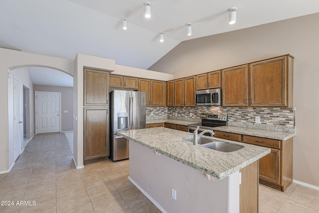 kitchen with backsplash, stainless steel appliances, a kitchen island with sink, sink, and lofted ceiling