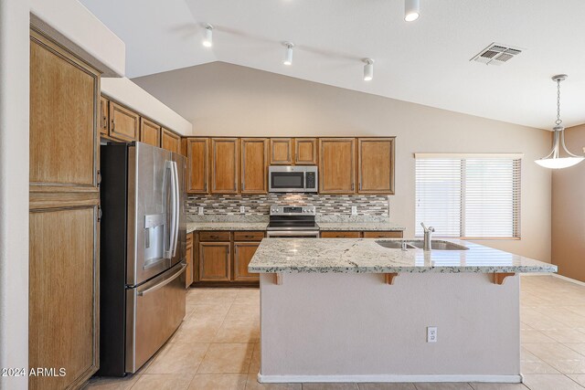 kitchen featuring pendant lighting, a kitchen island with sink, sink, vaulted ceiling, and appliances with stainless steel finishes