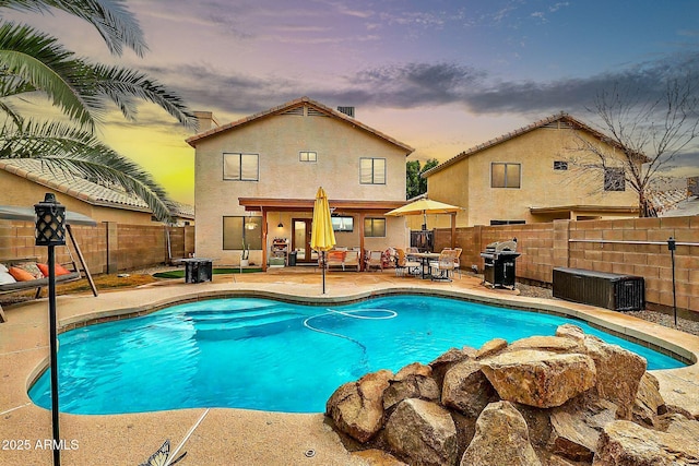 pool at dusk with a patio and a grill