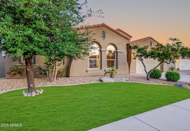 mediterranean / spanish home with a garage and a lawn