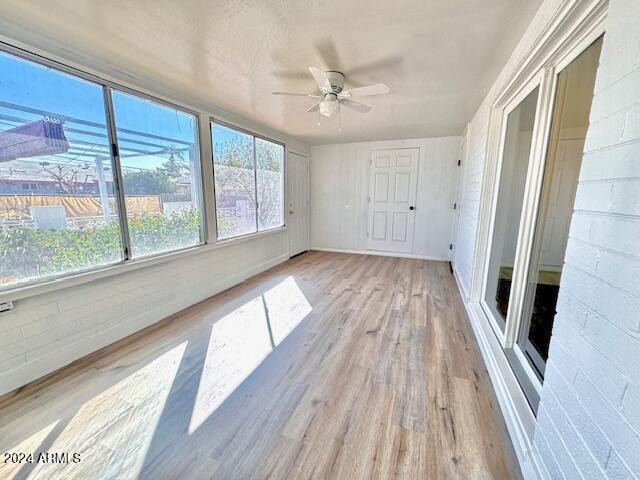 unfurnished sunroom with ceiling fan