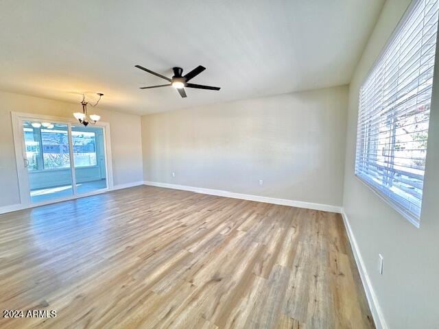 spare room with light hardwood / wood-style floors and ceiling fan with notable chandelier