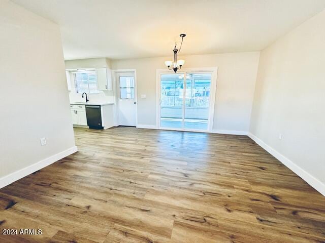 unfurnished dining area with light hardwood / wood-style floors, an inviting chandelier, and sink