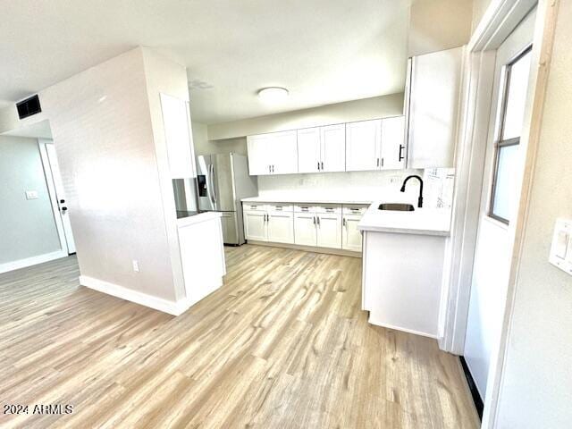 kitchen with decorative backsplash, stainless steel refrigerator with ice dispenser, sink, light hardwood / wood-style flooring, and white cabinets