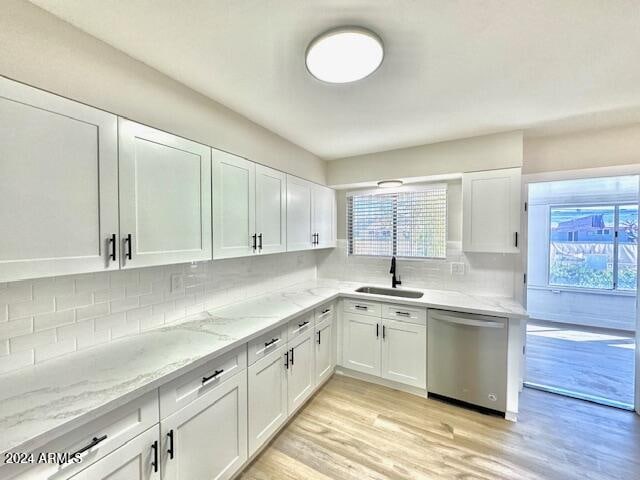 kitchen featuring sink, stainless steel dishwasher, decorative backsplash, light wood-type flooring, and white cabinetry