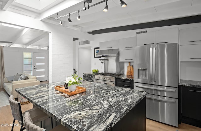 5809 N 10th Pl, Phoenix, AZ 85014 - kitchen featuring range hood, light wood-type flooring, beamed ceiling, and appliances with stainless steel finishes