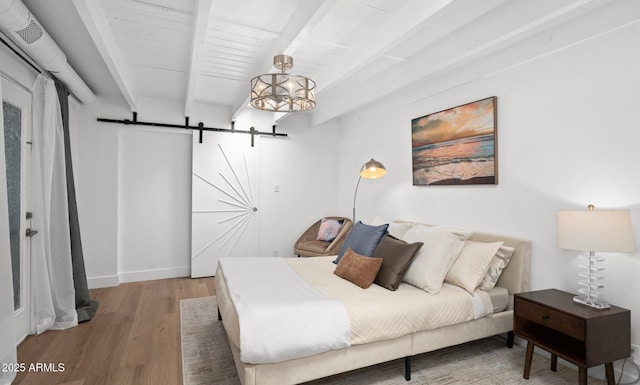 5809 N 10th Pl, Phoenix, AZ 85014 - bedroom with beam ceiling, baseboards, a barn door, and wood finished floors