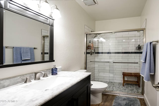 bathroom featuring hardwood / wood-style flooring, toilet, vanity, and a shower with shower door