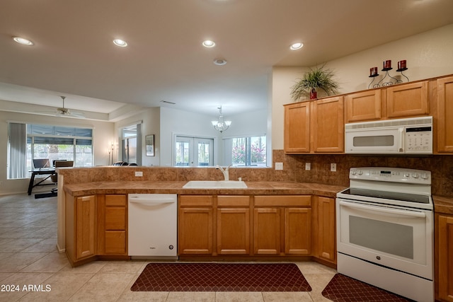 kitchen with kitchen peninsula, white appliances, plenty of natural light, and sink