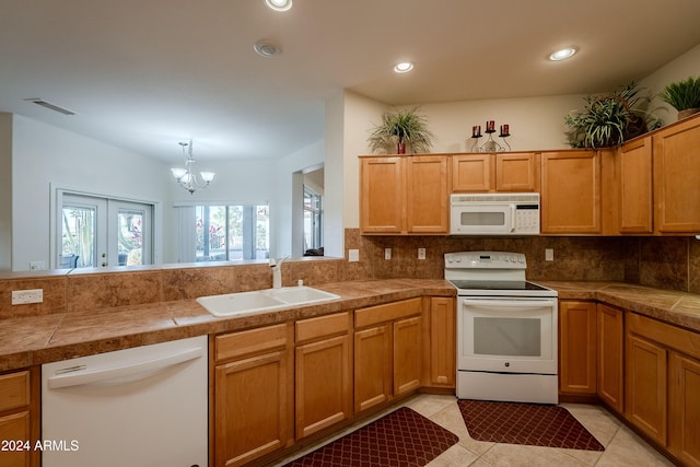 kitchen featuring white appliances, sink, light tile patterned floors, tasteful backsplash, and a chandelier