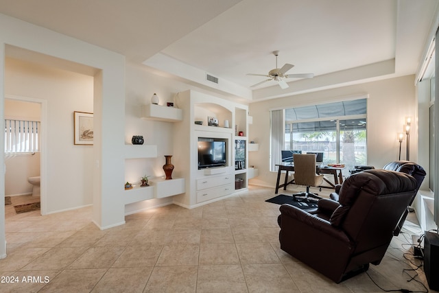 tiled living room featuring a tray ceiling, ceiling fan, and built in features