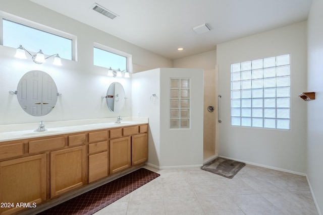 bathroom featuring tile patterned flooring, plenty of natural light, a shower, and vanity