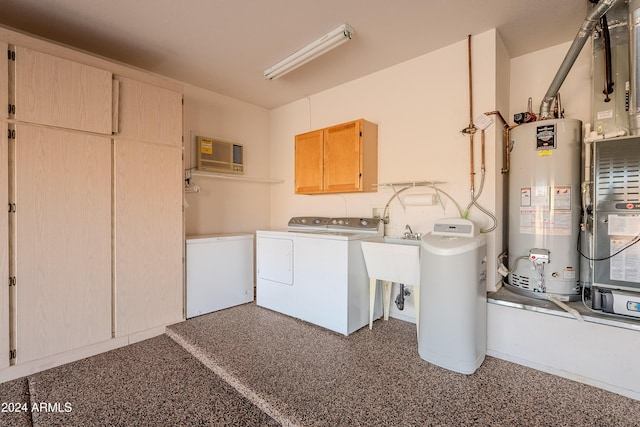 clothes washing area featuring cabinets, sink, washing machine and clothes dryer, and water heater